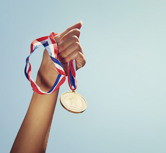 Hand hält Gold-Medaille
